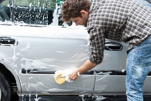 Young handsome guy cleaning his silver auto